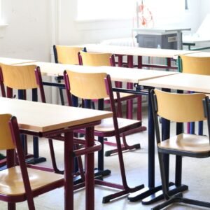 A bright empty classroom with wooden tables and chairs, ready for students.