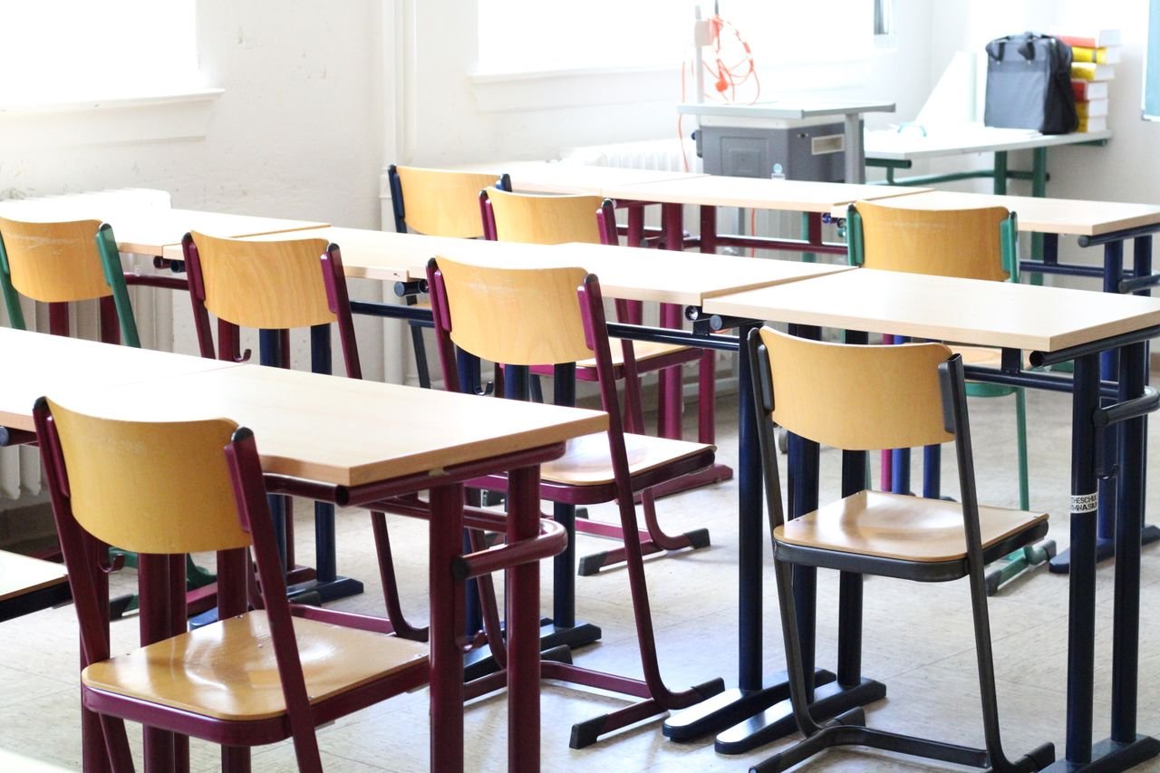 pexels photo 12168815 12168815 A bright empty classroom with wooden tables and chairs, ready for students.